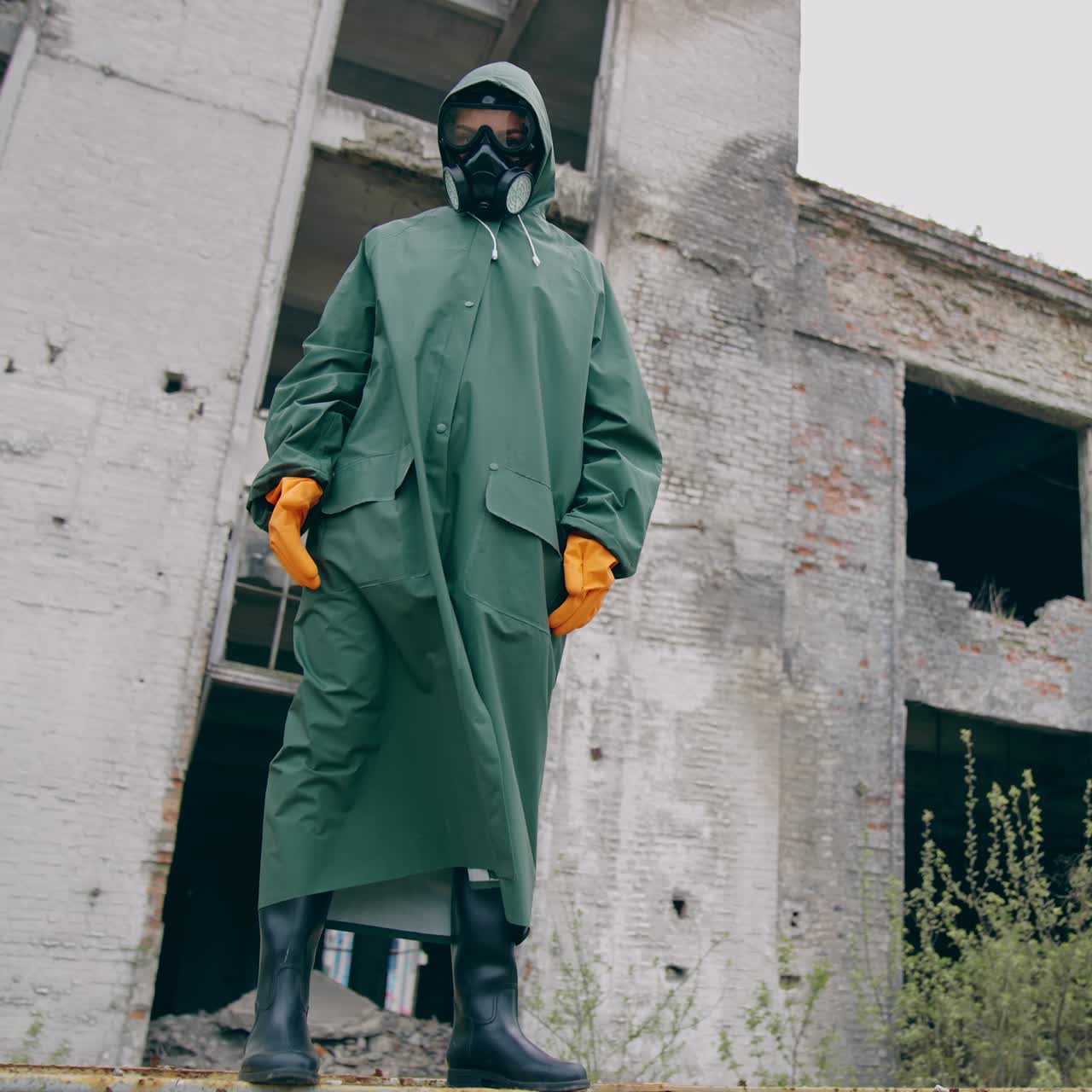 Person in protective suit standing in ruined city. Man in biohazard suit