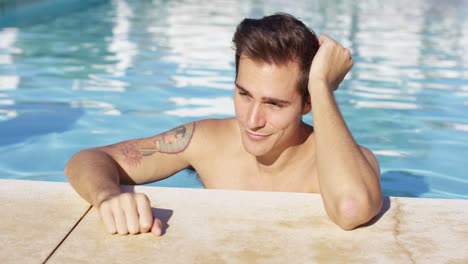 hombre de pie solo en la piscina y sonríe a la cámara