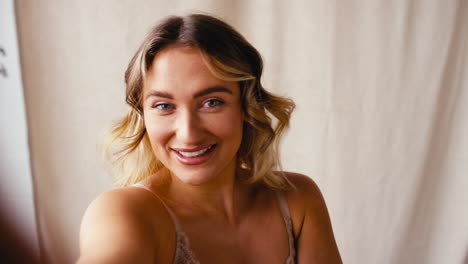 pov studio shot of confident natural woman in underwear making funny faces and posing for selfie
