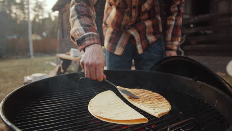 hombre asando tortillas en barbacoa al aire libre