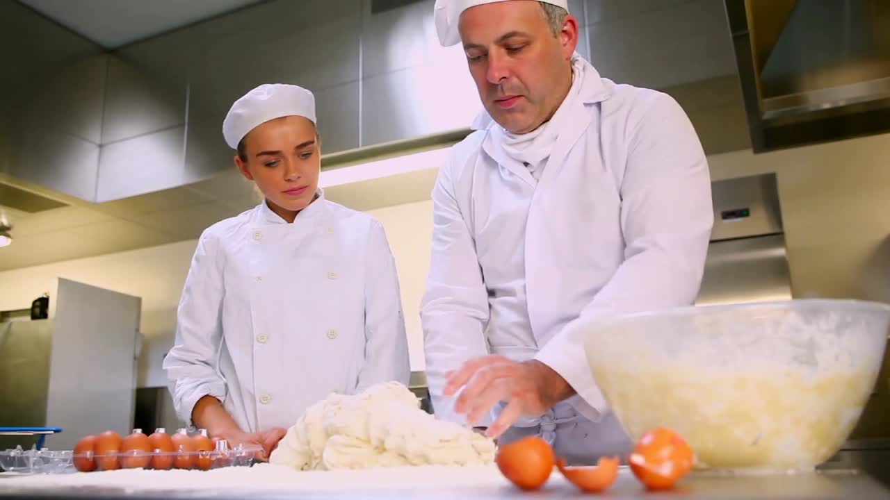 jefe de cocina mostrando al aprendiz cómo preparar la masa