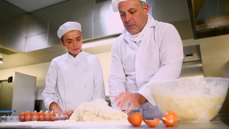 head chef showing trainee how to prepare dough