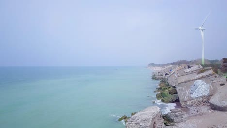 Aerial-view-of-abandoned-seaside-fortification-buildings-at-Karosta-Northern-Forts-on-the-beach-of-Baltic-sea-in-Liepaja,-Latvia,-calm-sea-on-a-sunny-day,-wide-angle-drone-shot-moving-forward