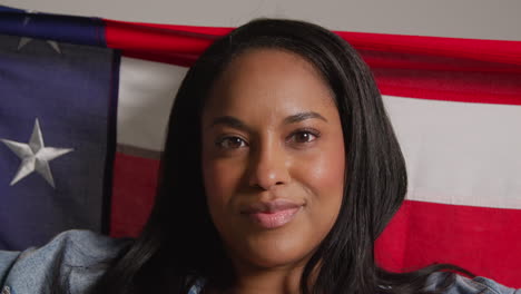 close up studio portrait shot of woman holding american flag behind her celebrating 4th july independence day