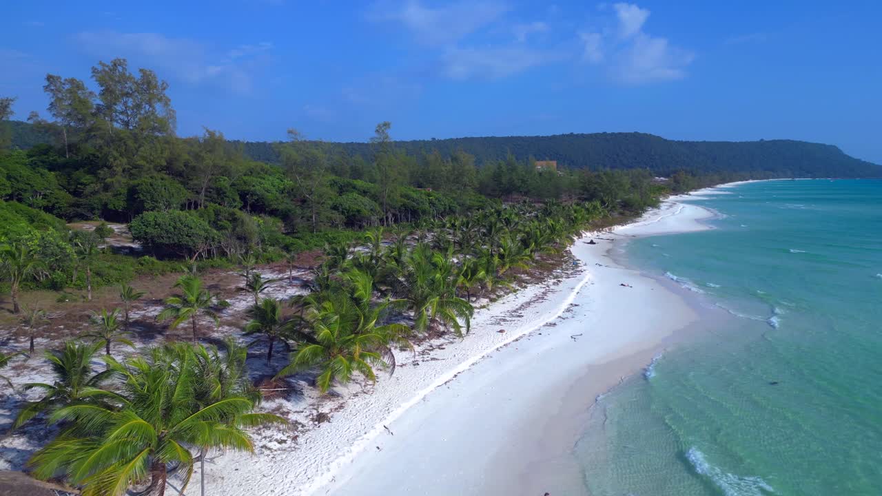 Crystal clear turquoise water and white sand beach, lined with lush palm trees and a lone tourist enjoying the serene tropical paradise. Amazing aerial view flight fly reverse drone