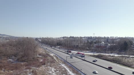 Los-Drones-Vuelan-Sobre-El-área-Suburbana-De-Vancouver-Con-El-Tráfico-De-Camiones-Conduciendo-En-La-Carretera-Principal-Durante-El-Día-Soleado