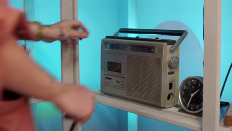 a person is inserting a cassette tape into a vintage portable radio-cassette player - close up