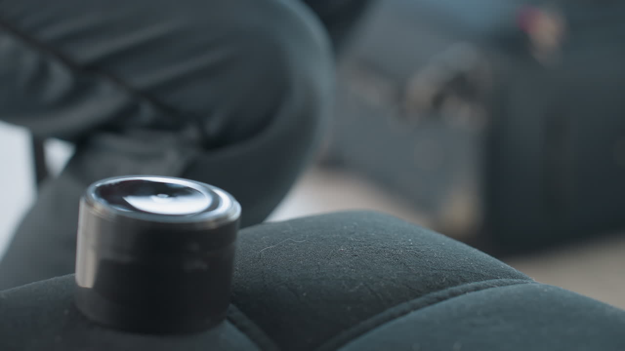 close up of makeup kit with hand taking foam applicator from black box on cushioned seat with blurred item on floor, bright studio interior with soft natural light highlight container and tool