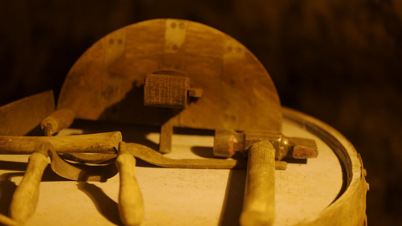 Wooden mallet striking oak whiskey cask lid with traditional tools in rustic distillery workshop