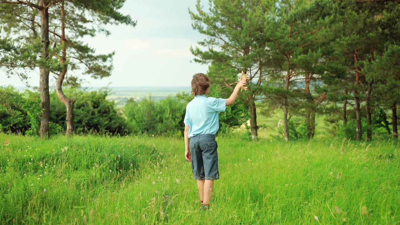 흐린 날 공원에서 나무 비행기 장난감을 가지고 놀고 있는 행복한 어린 소년