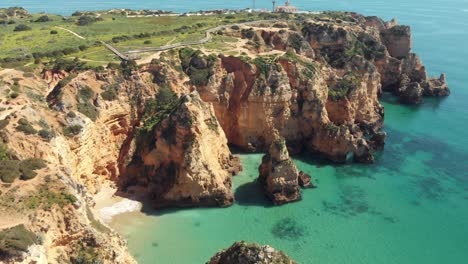 distant view of ponta da piedade lighthouse overlooking the atlantic ocean and eroded cliffs, lagos, algarve