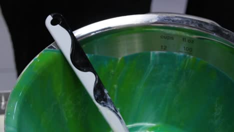 mixing ingredients in a green bowl with a spatula