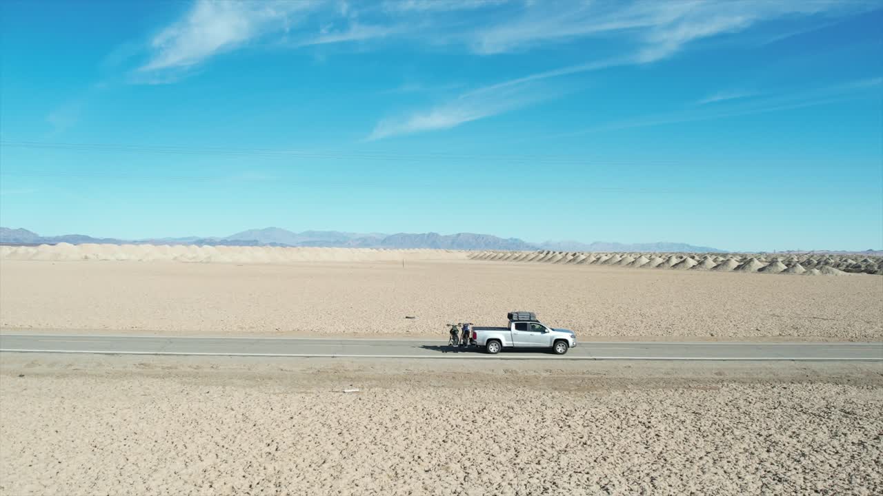 A drone follow shot of a truck along a quiet highway in central USA with simple power lines