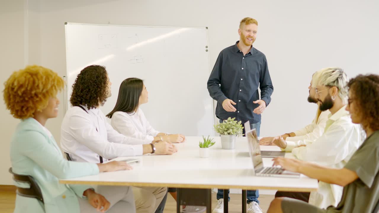 Man leading a meeting in a coworking using a board