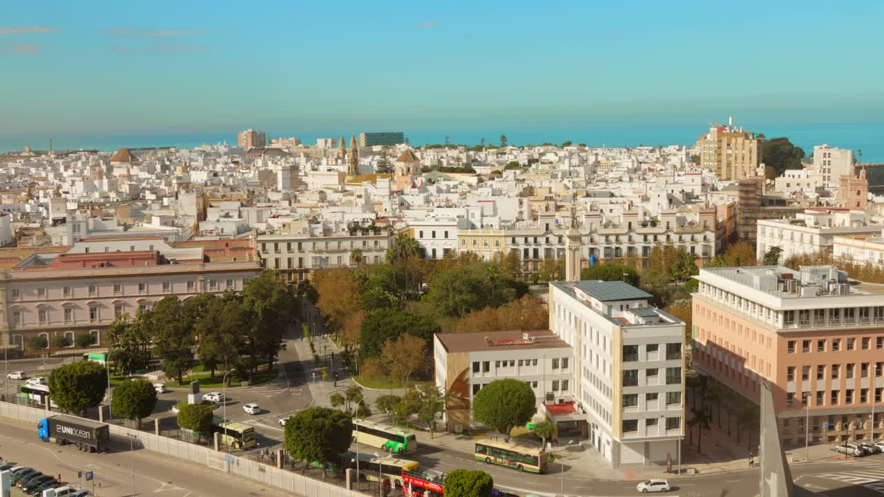A high angle drone shot. The Lively atmosphere of Cadiz, Spain, showcasing bustling traffic, stunning buildings, and the beautiful coastal landscape. A glimpse of city life in this historic port town.