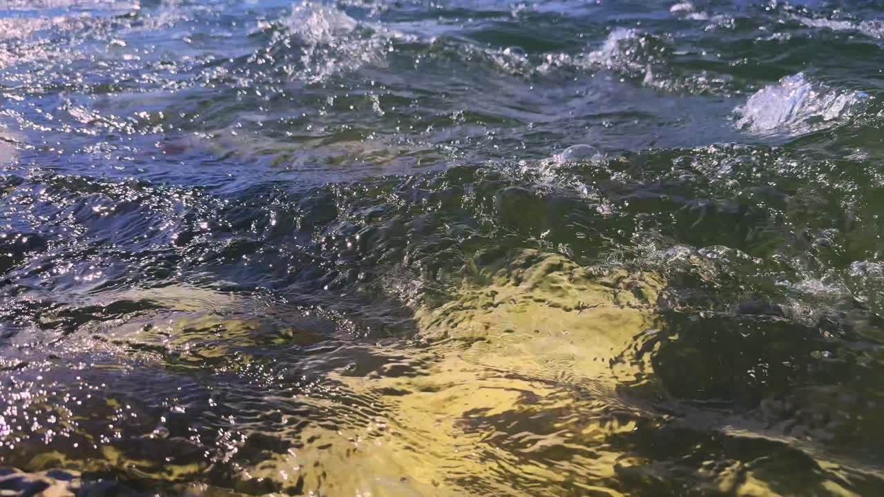 Underwater Scene Featuring Gentle Waves and Submerged Rocks Glimmering Under Sunlight, Capturing the Tranquil Beauty of Nature and Water Reflections