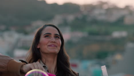 beautiful young caucasian woman blowing bubbles on rooftop at sunset young man kissing girlfriend enjoying playful intimacy with city in background