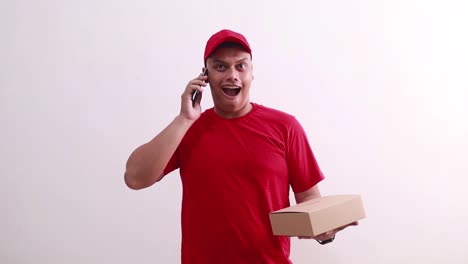 young asian courier man holding a cardboard while talking on the phone