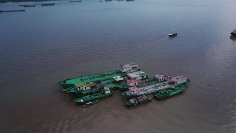 Toma-Aérea-De-Barcos-De-Trabajo-Anclados-Cerca-De-La-Costa-En-Un-Día-Claro-Y-Soleado