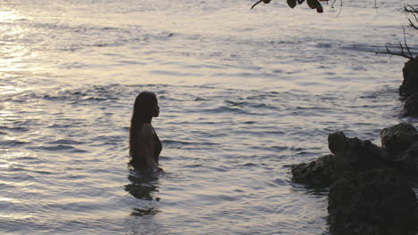 latin girl at sunrise bathes in tranquil early morning coastal sea waters, static shot