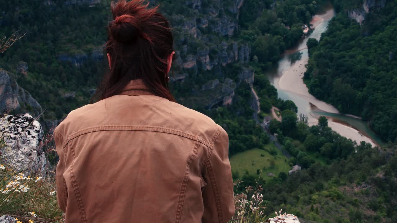 A woman stands still, le point sublime observing the meandering river far below.