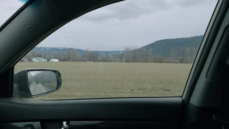 view from a moving car of open field and distant hills