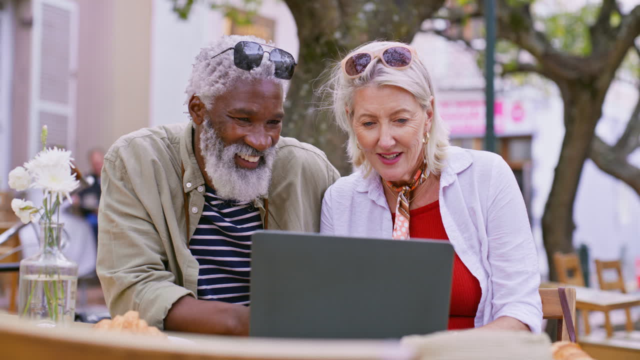 Mature couple using laptop at outdoor cafe