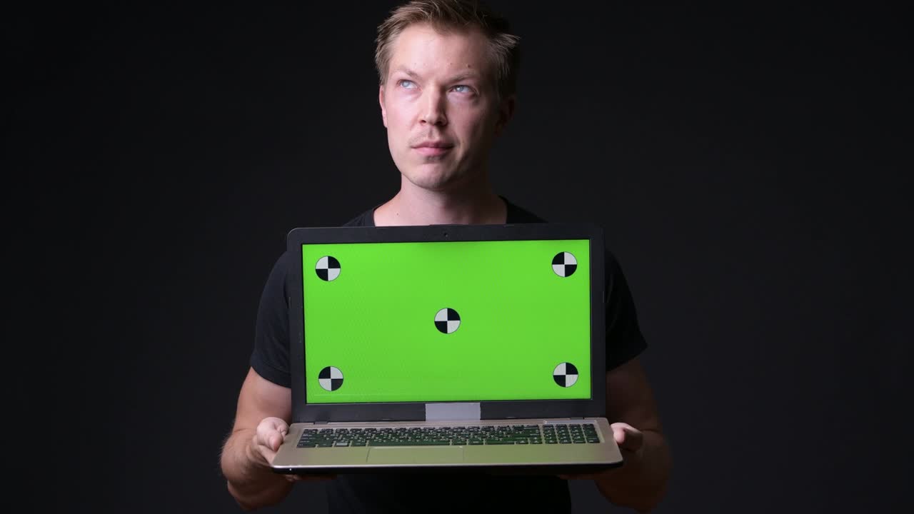 hombre sosteniendo una computadora portátil con pantalla verde de clave de croma