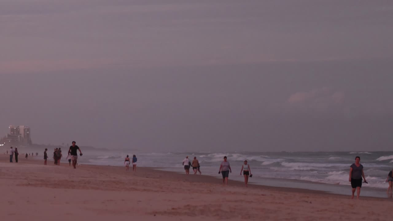 해가 지는 해변에서 산책하는 사람들, 배경의 건물