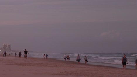people strolling on beach at sunset, buildings in background