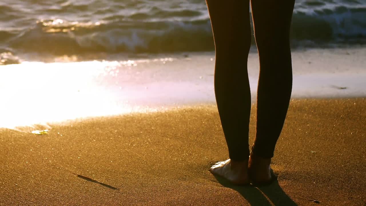 Parte inferiore del corpo di una donna che pratica yoga sulla spiaggia