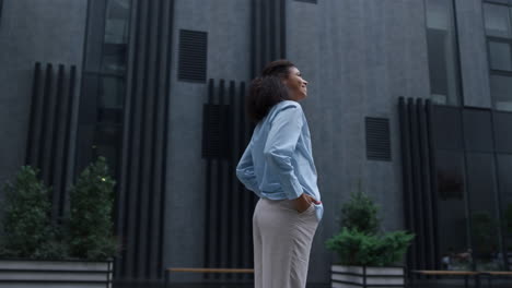 smiling woman standing at modern office building looking in camera. proud winner