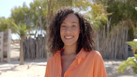 portrait of happy biracial woman looking at camera at beach house