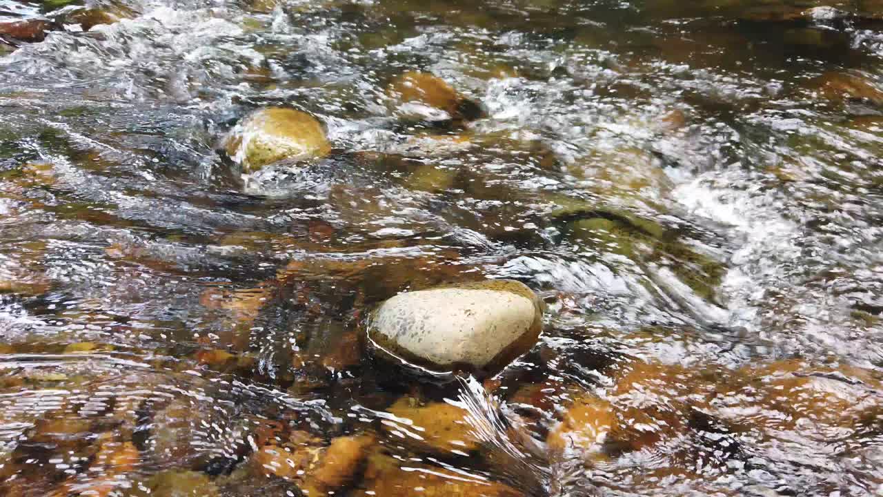 aguas blancas cristalinas que fluyen río abajo sobre piedras y guijarros que forman el lecho del río