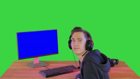 excited gamer with headphones smiling to the camera on a green screen, chroma key