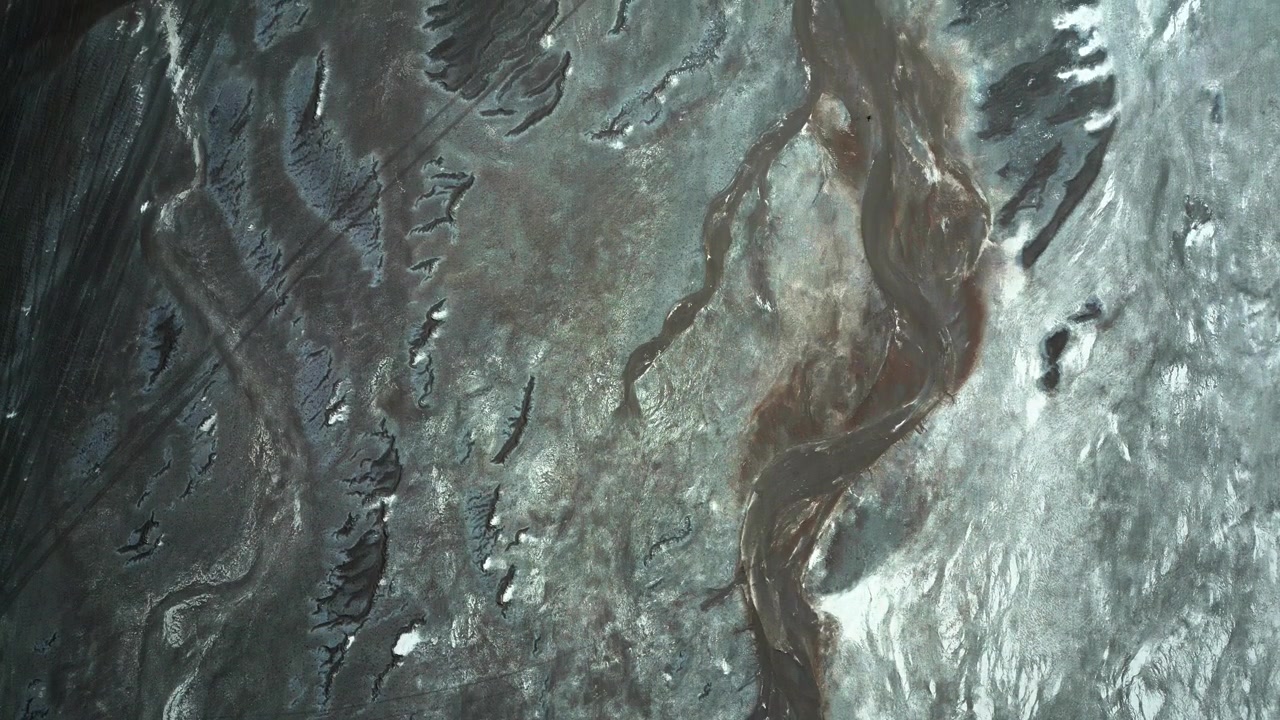 Top down aerial view of Salar de Quisquiro silver salt crust with winding dark sediment channels and abstract geological patterns resembling natural artwork. Salar de Quisquiro, Chile