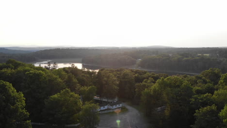 Drone-ascends-to-reveal-lake-and-mountains-behind-trees-at-golden-hour