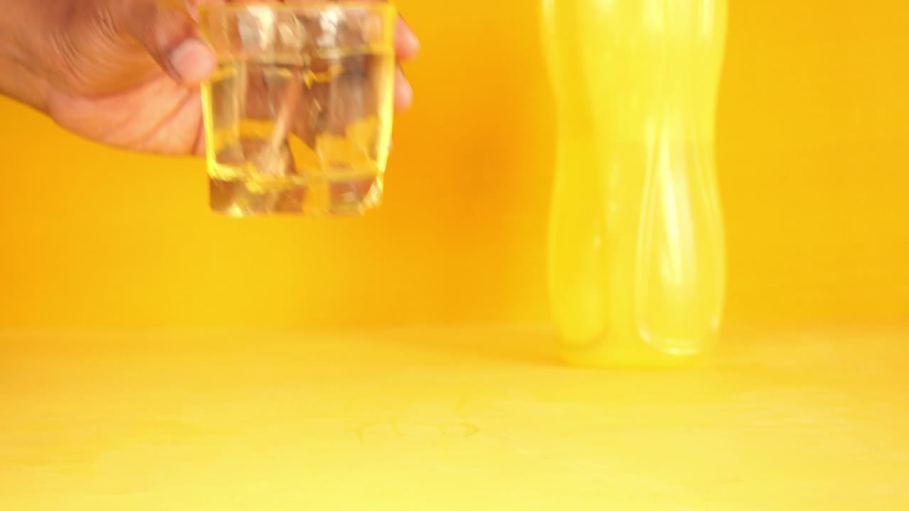 노란색 배경에 물 한 잔을 들고 있는 손 ,