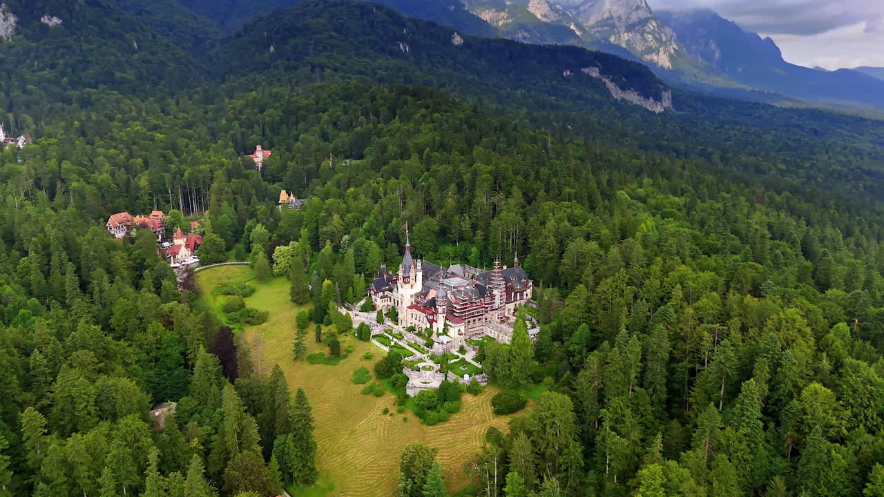 Territory of the spectacular castle in the green pine wood growing in the mountains. Drone flight high above the Peles Castle in Prahova County, Romania