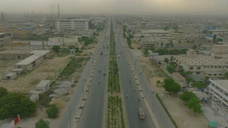 aerial drone top down shot over two way road with godowns and factories on both side in korangi industrial area, karachi, pakistan