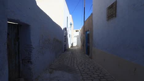 a narrow alley with light blue walls in the ancient city of tunisia on a sunny day