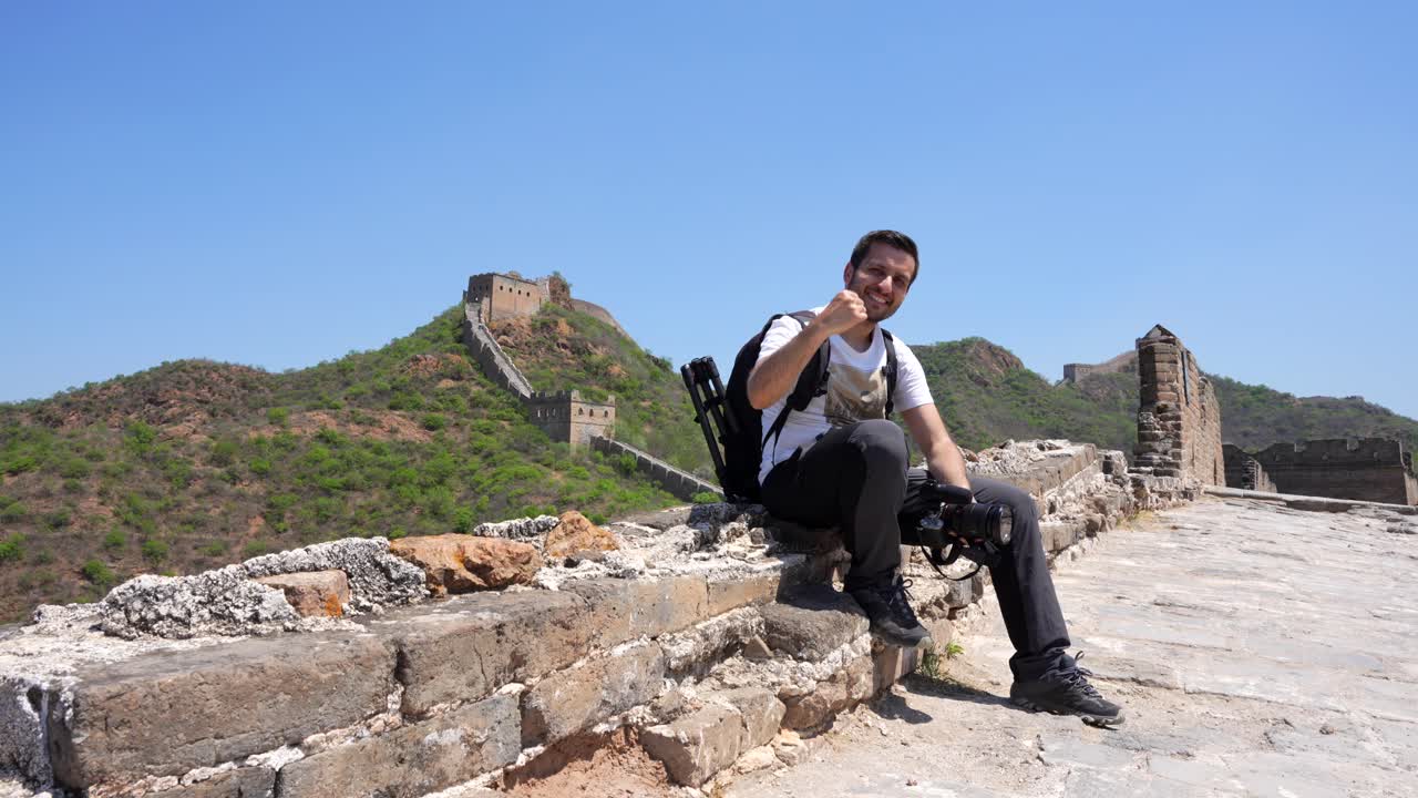Happy tourist man on the edge of the Great Wall making an achievement gesture