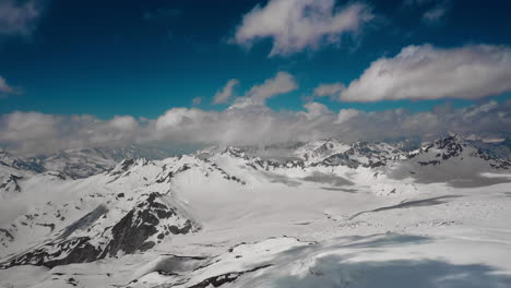 air flight through mountain clouds over beautiful snow-capped peaks of mountains and glaciers.