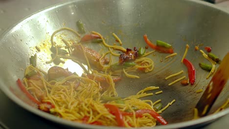 CU-Slow-motion-Cook-prepares-noodles-pasta-in-a-frying-pan-in-oil-with-fresh-vegetables