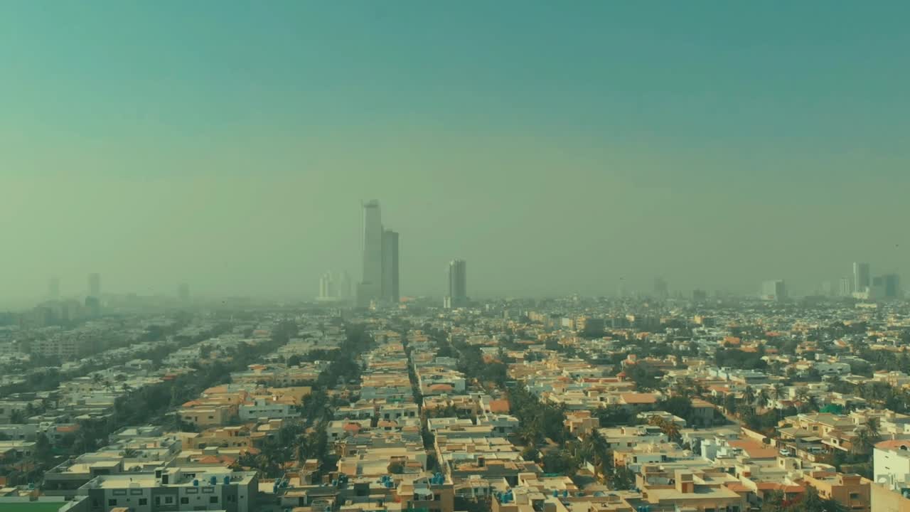 Aerial Over Housing With Bahria Icon Tower In The Distance In Karachi Covered In Smog. Pedestal Up