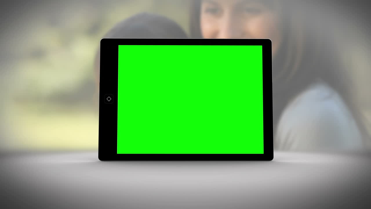 tableta con pantalla verde frente a la familia al aire libre