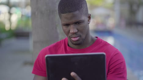 man watching football match on tablet, feeling disappointed
