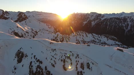 chamrousse french alps with sunrise between the peaks, aerial flyover approach shot