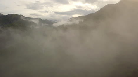 Aerial-view-flying-thru-the-morning-rain-cloud-covered-tropical-rain-forest-mountain-landscape-during-the-rainy-season-on-the-Doi-Phuka-Mountain-reserved-national-park-the-northern-Thailand