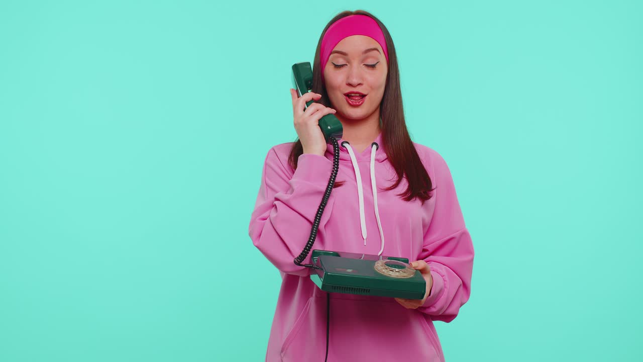 Cheerful teen girl secretary talking on wired vintage telephone of 80s says hey you call me back